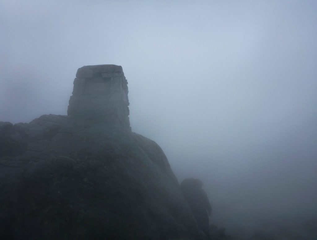 The cairn marking the summit on the Chilkoot Trail covered in fog