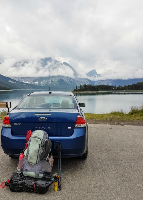 A backpack rests against a car in a parking lot