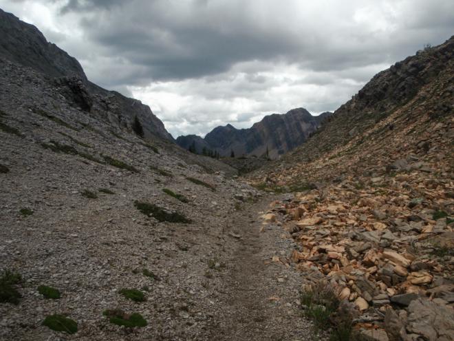 A rocky trail winds through mountains on a cloudy day