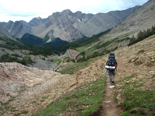 A man walks a mountain trail with a backpack