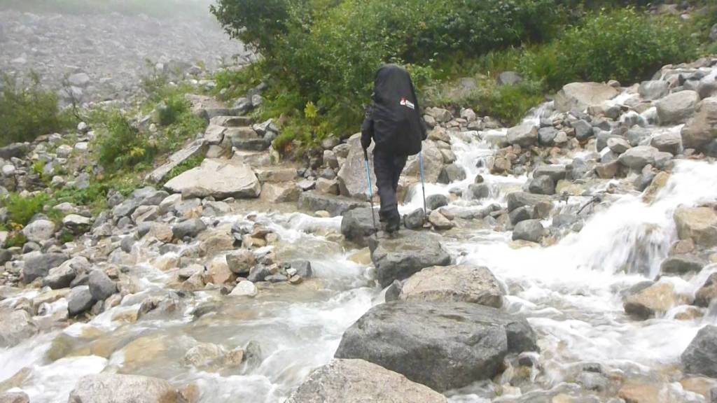 A man crosses a river on the Chilkoot Trail