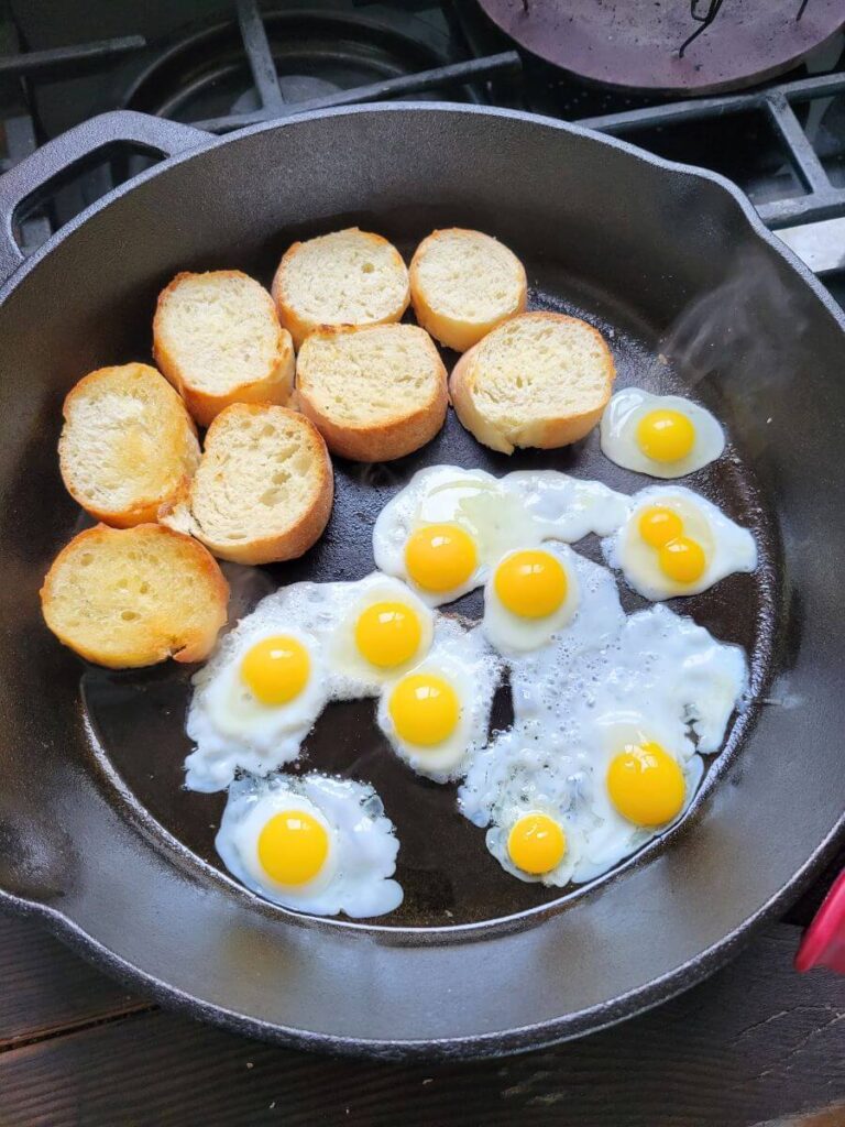 Quail eggs and baguette rounds cook in a cast iron pan