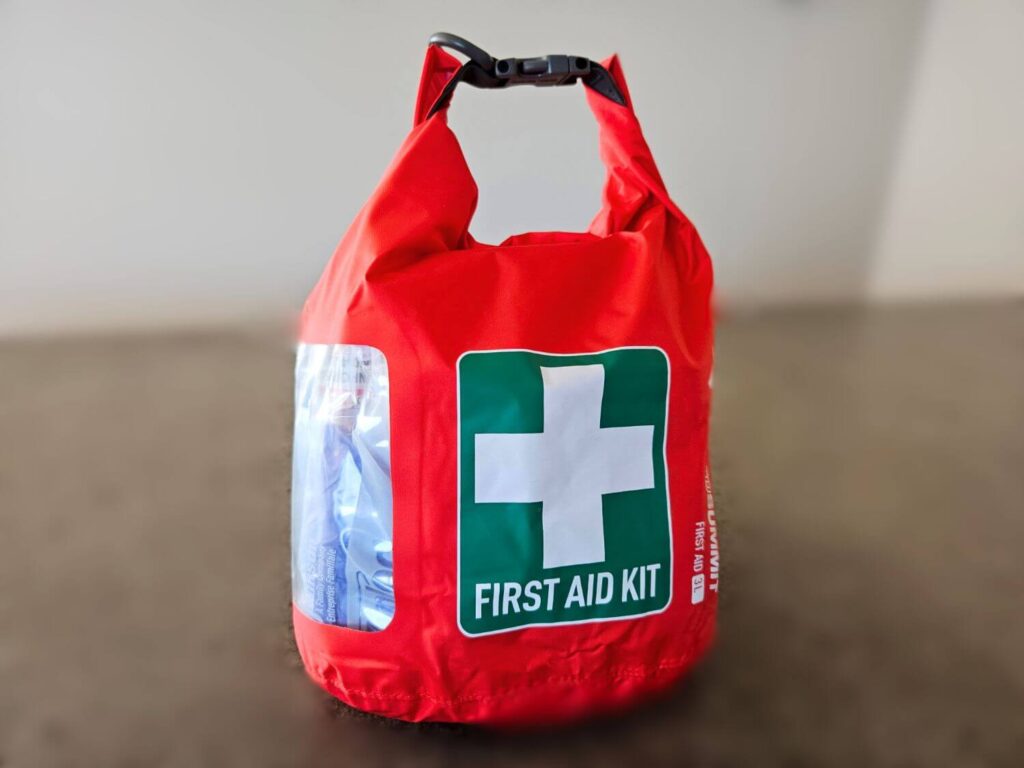 A bright red dry bag with a green and white first aid kit symbol