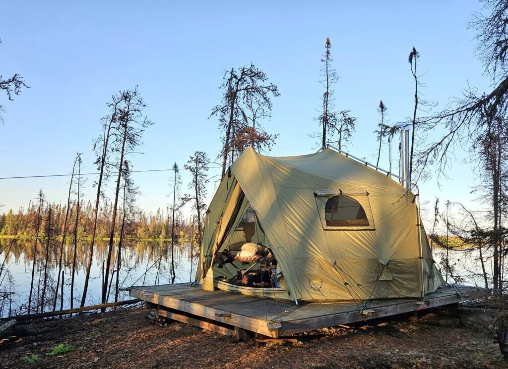 A tent sits on a platform with a lake in the background