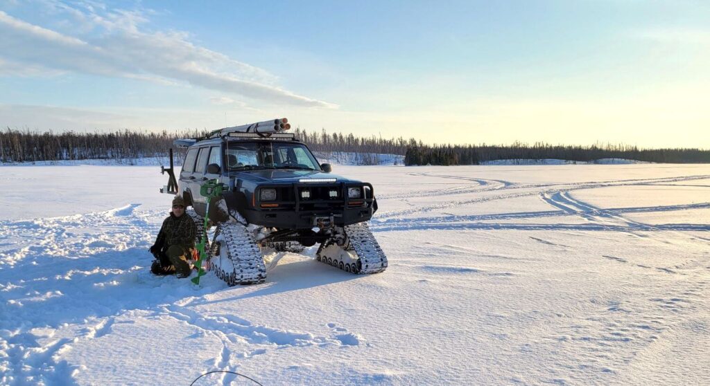 A jeep cherokee on tracks sits on a frozen lake